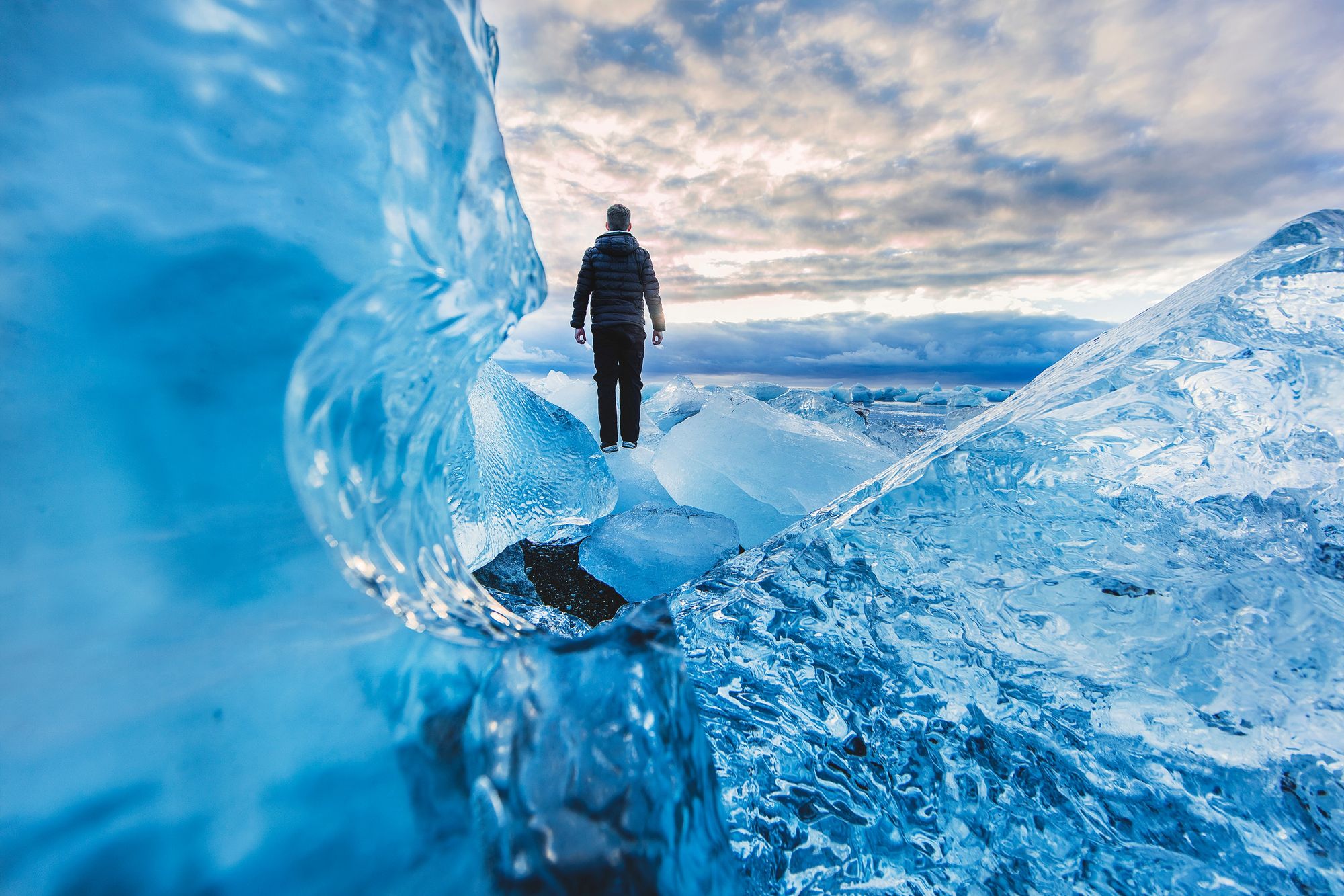 A person standing atop a glacier, looking toward the horizon